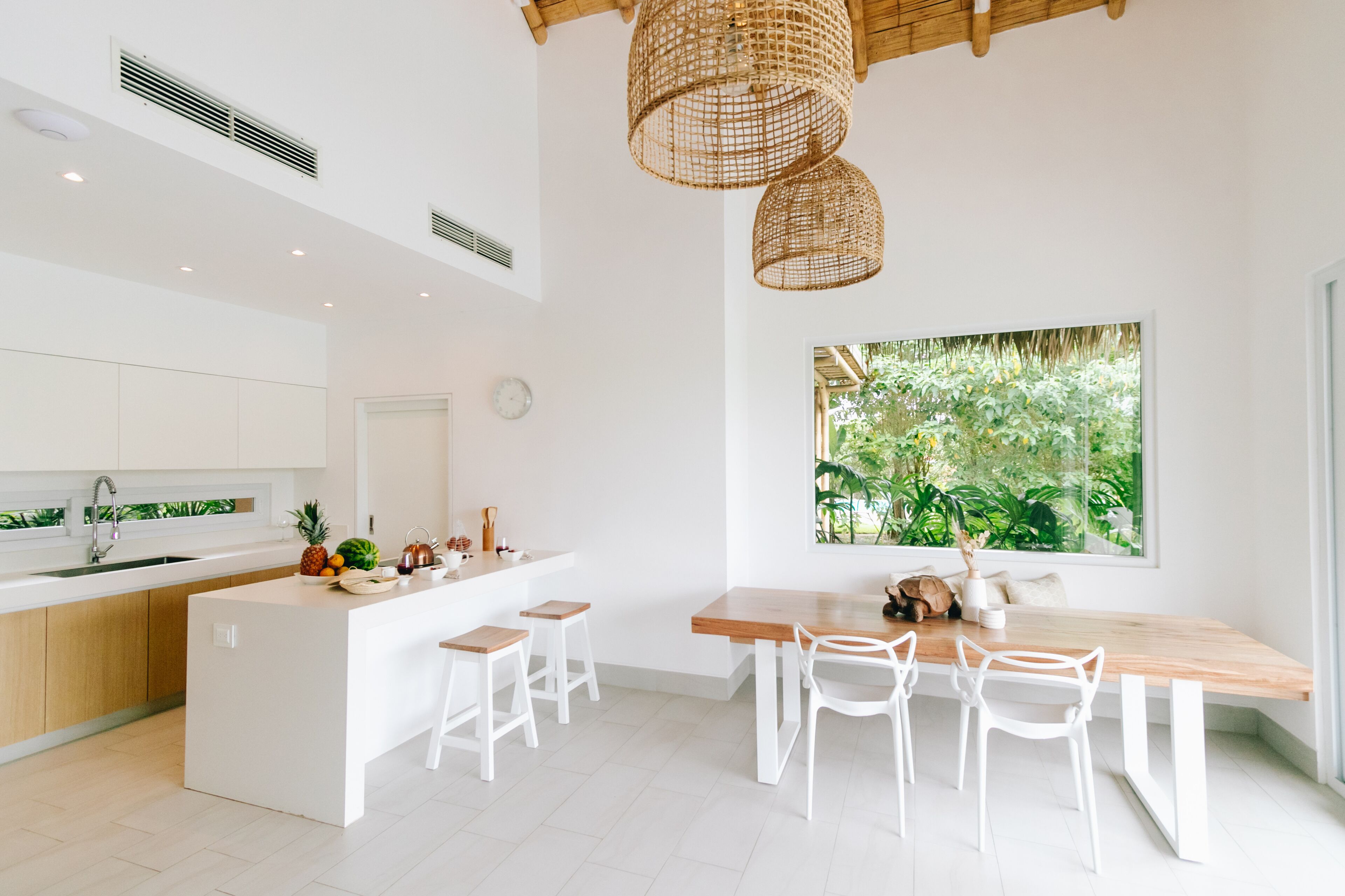 A modern kitchen with white cabinetry, a wooden island, and a large window with a view of greenery.