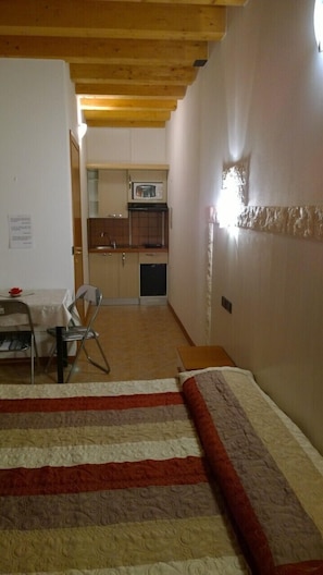 Un dormitorio con cama, una kitchenette pequeña y una zona de comedor.