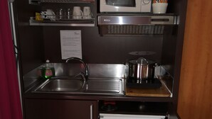 Une petite cuisine équipée d’un four à micro-ondes, d’un évier et d’un petit réfrigérateur.