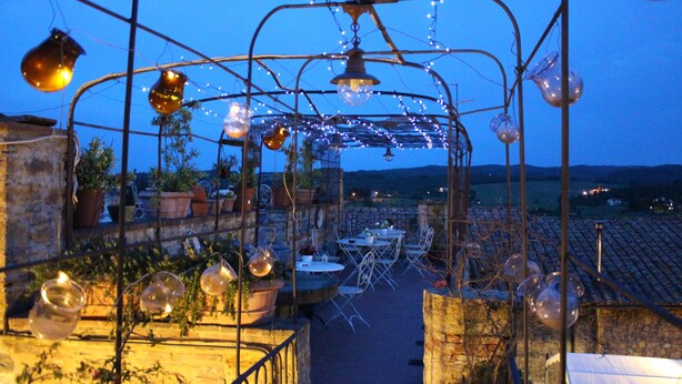 Un patio al aire libre con mesas y sillas, luces colgantes y globos de vidrio.