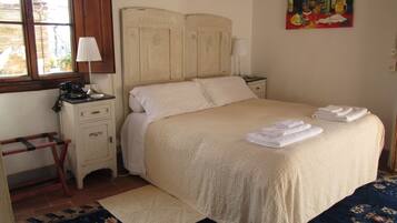 A bedroom with a bed, bedside tables, a lamp, a painting, and a window.