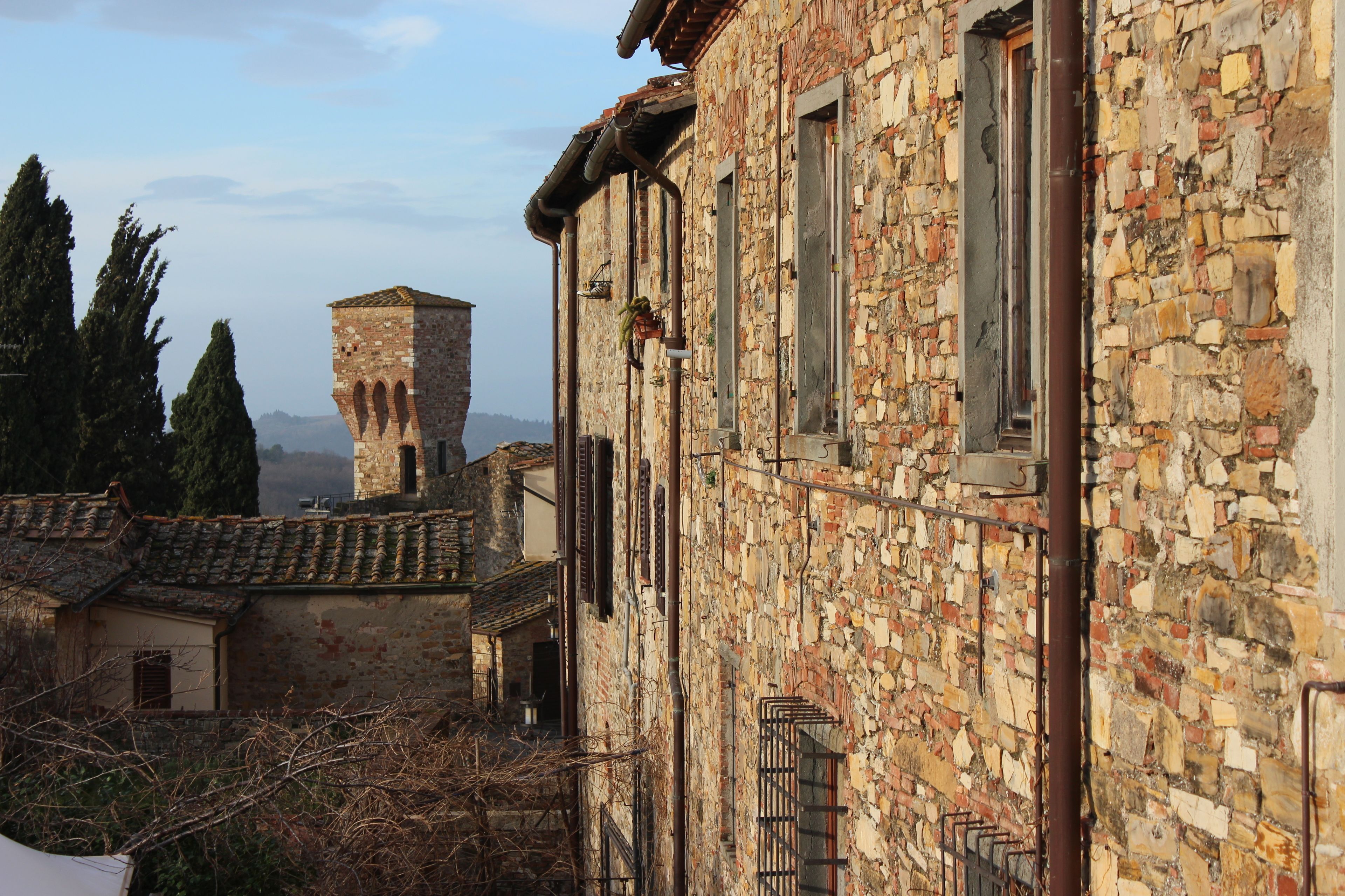 A stone building with arched windows and a tower in the background.