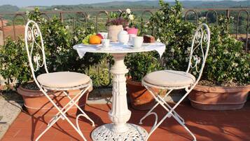 Enjoy a serene outdoor space with a table and chairs, surrounded by lush plants and breathtaking views of the surrounding hills.