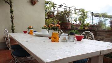 Ein weißer Tisch mit Stühlen, einer Vase mit Blumen, einer Karaffe und einer Schüssel.
