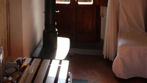 Una habitación con puerta de madera, una silla blanca y una ventana con cortinas.