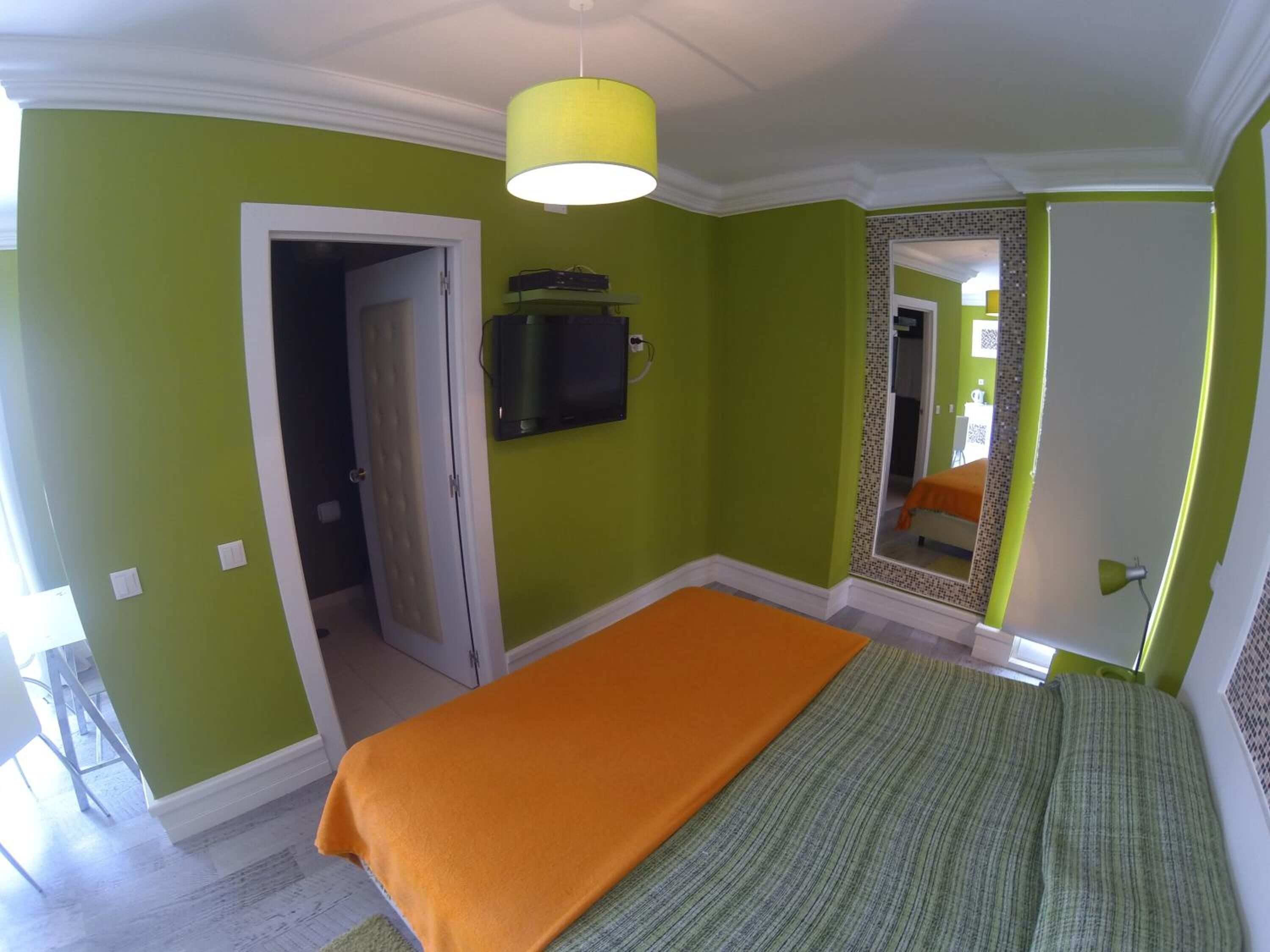 A bedroom with a bed, a television, and a mirror.