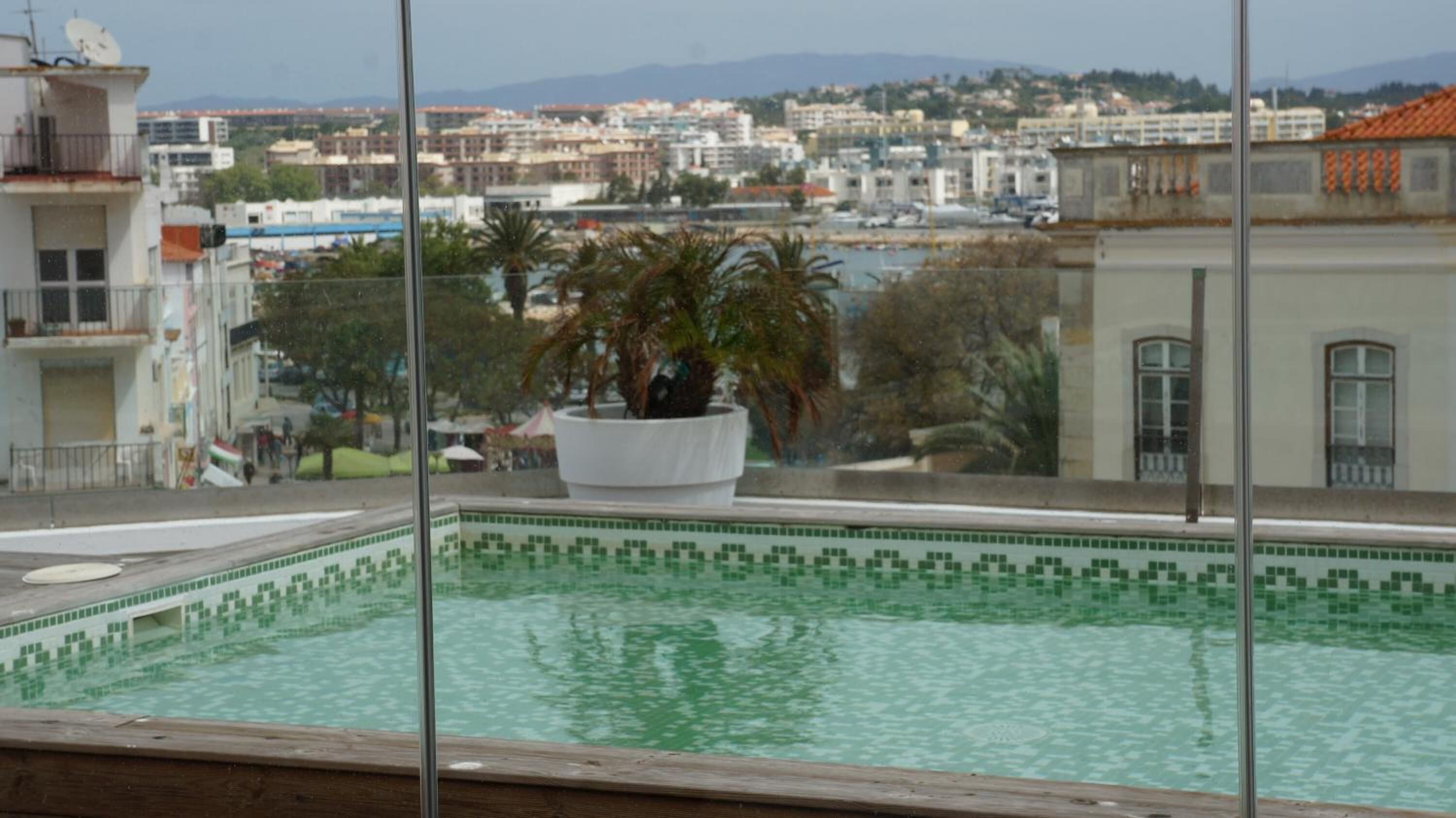 A swimming pool with a tiled edge and a view of a cityscape in the background.