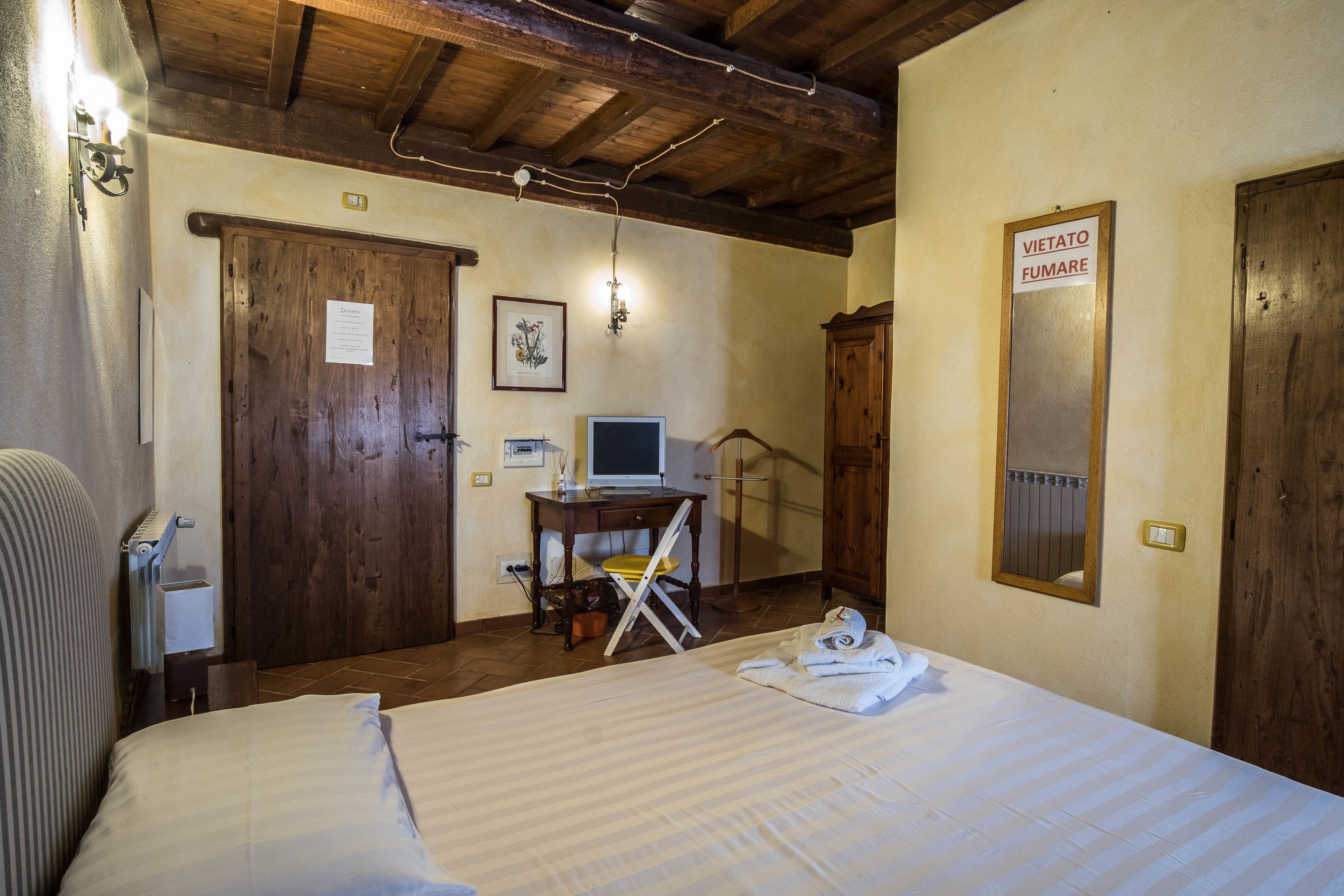 Habitación de hotel con cama, escritorio con computadora, silla y armario de madera.