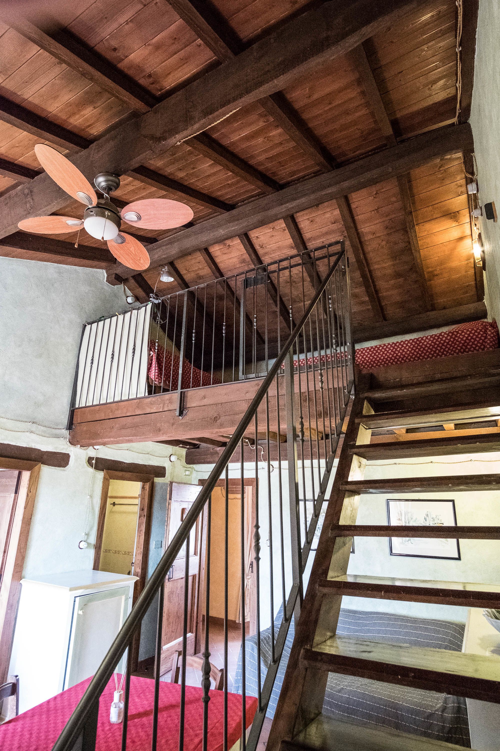 A wooden staircase with a metal railing leading to a balcony.