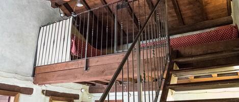 A wooden staircase with a metal railing leading to a balcony.