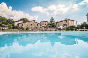 Une piscine avec des bâtiments en pierre en arrière-plan.