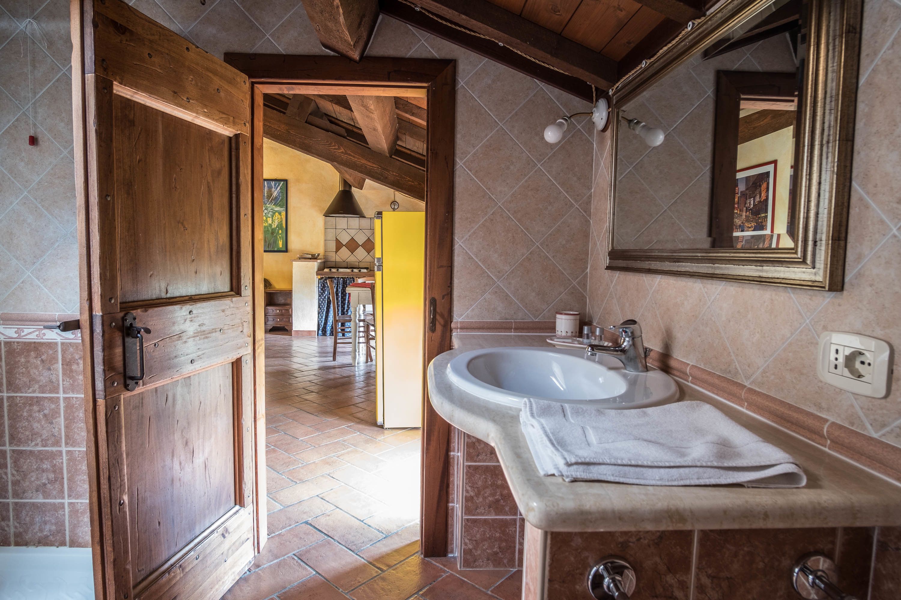 A bathroom with a wooden door, a sink, and a mirror.