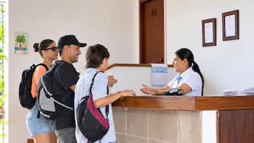 A reception desk with a receptionist, a man, and two women standing in front of it.