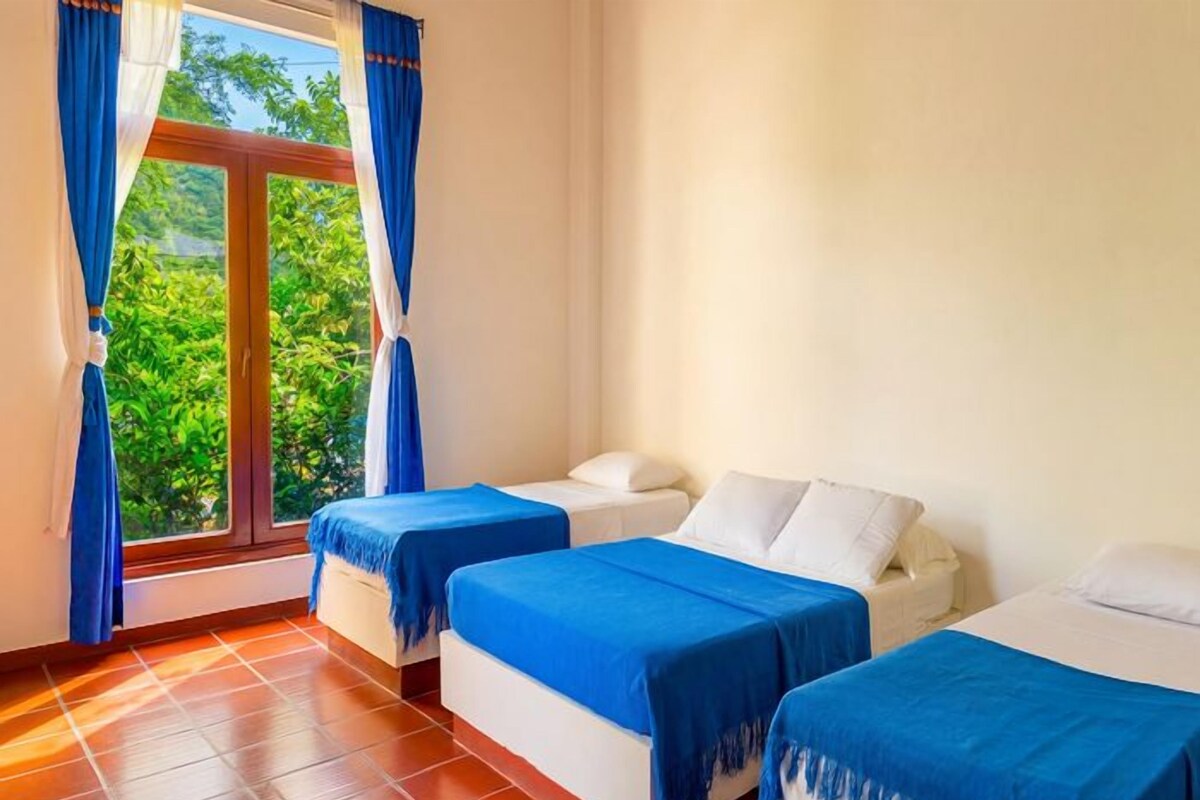 A hotel room with two beds, a window with curtains, and a tiled floor.