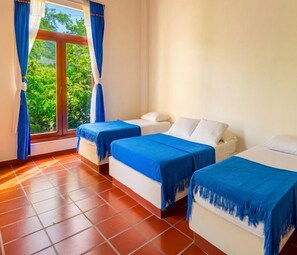 Una habitación de hotel con dos camas, una ventana con cortinas y piso de baldosas.