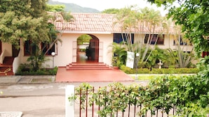 A two-story building with a red-tiled roof, a central entrance with steps, and a gated driveway. - Hotel y Parque Acuatico Agua Sol Alegría (Honda)