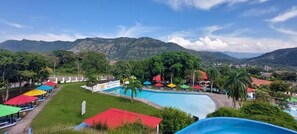 A resort with a swimming pool, outdoor seating, and a mountainous backdrop. - Hotel y Parque Acuatico Agua Sol Alegría (Honda)