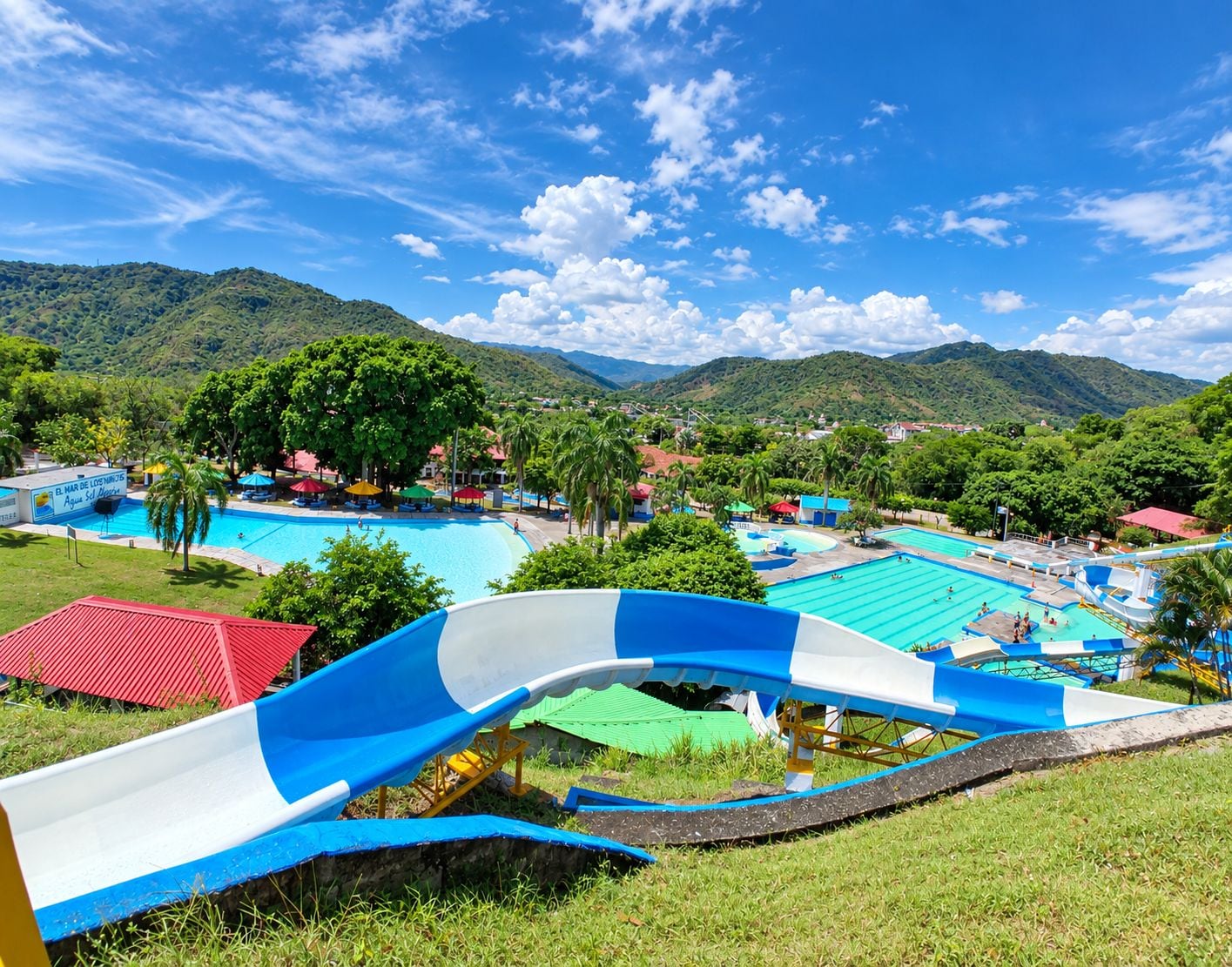 A water park with multiple pools and a large blue and white slide.