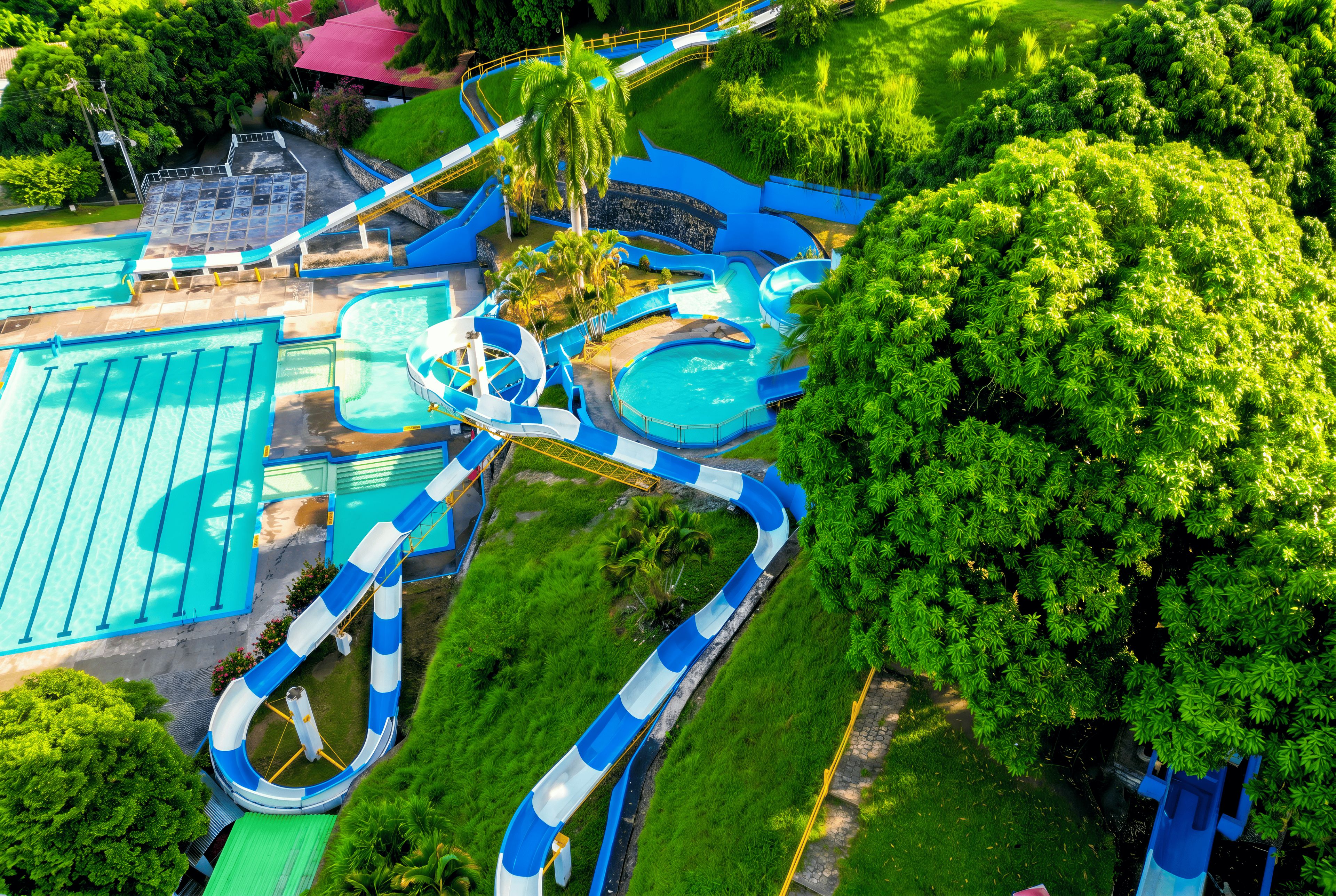 Parque acuático con múltiples toboganes y piscinas, rodeado de exuberante vegetación.
