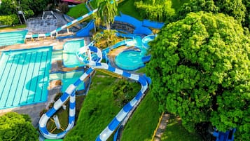 Parque acuático con múltiples toboganes y piscinas, rodeado de exuberante vegetación.