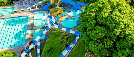 A water park with multiple slides and pools, surrounded by lush greenery.