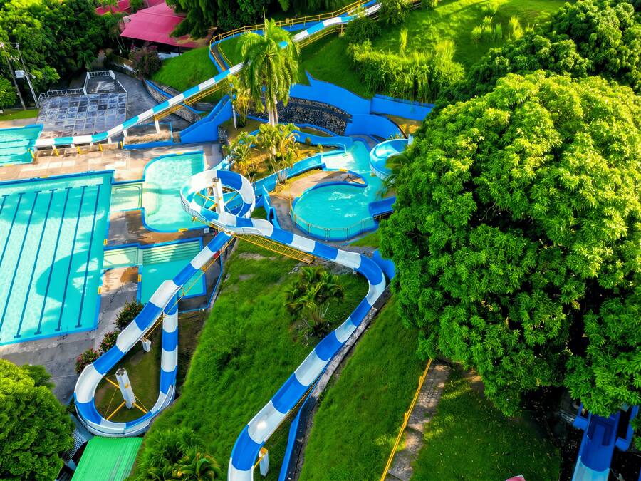 A water park with multiple slides and pools, surrounded by lush greenery.
