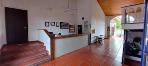 Un área de recepción con una escalera de madera, un mostrador de recepción y piso de baldosas.
