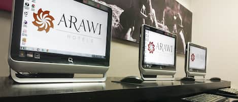 Three monitors displaying the Arawi Hotels logo, a desktop keyboard, and a mouse.