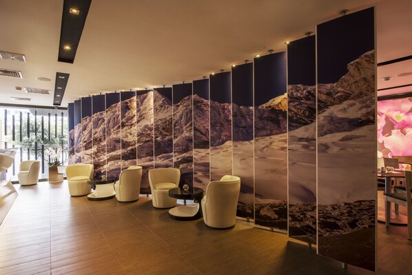 A modern lobby with a mountain-themed wall, comfortable seating, and a wooden floor. - Arawi Miraflores Prime (Lima)