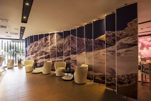 A modern lobby with a mountain-themed wall, comfortable seating, and a wooden floor.