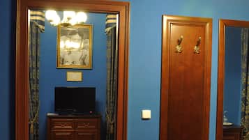 Ein Zimmer mit einem Holzkasten, einem Fernseher, einem gerahmten Foto, einem Spiegel und einer Holztür.