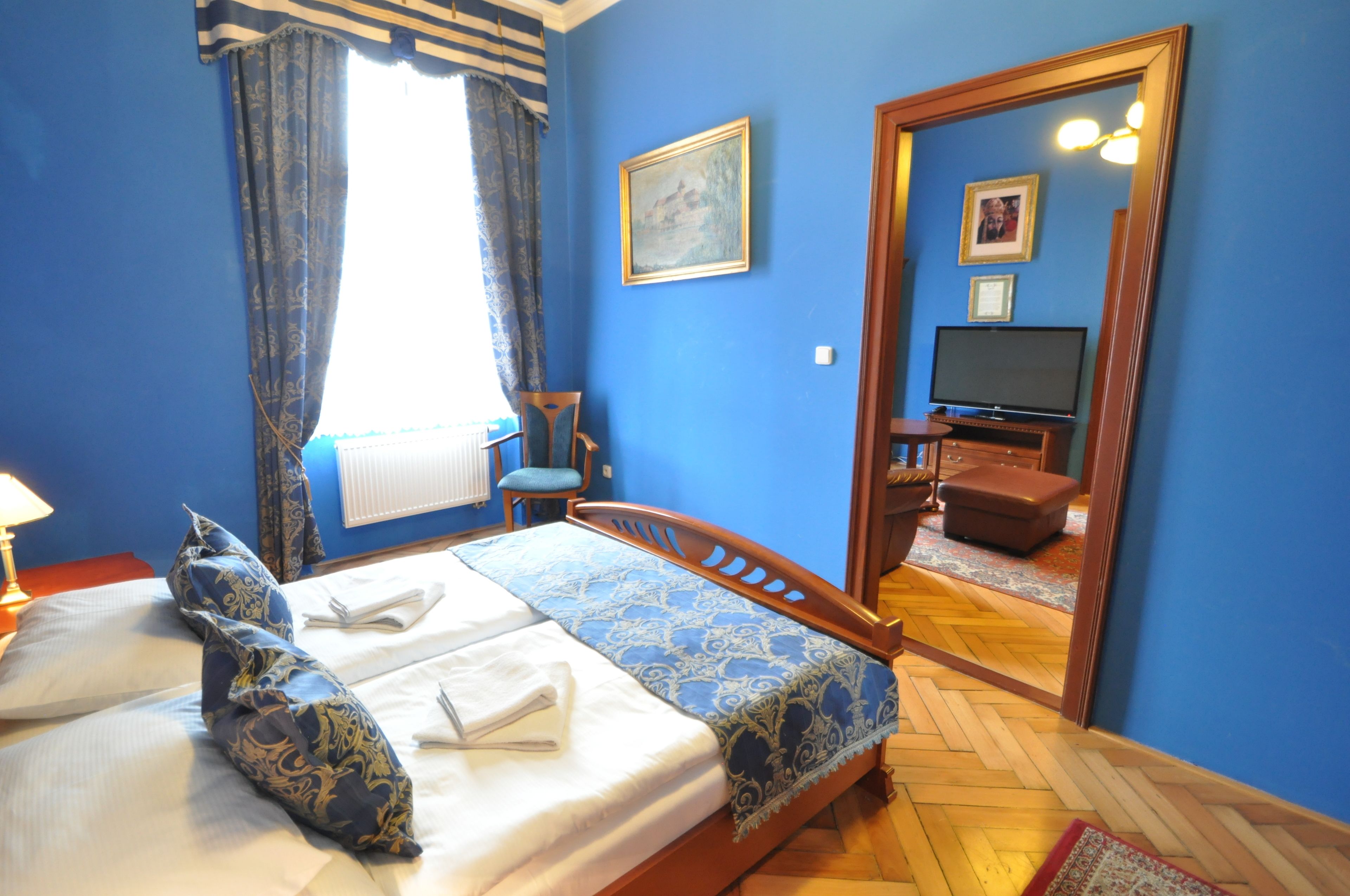 Una camera d'albergo con un letto, una sedia, una TV e uno specchio.
