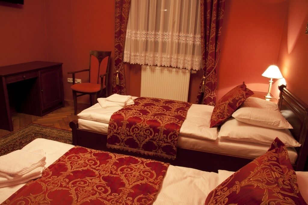 Una habitación de hotel con cama, una silla, un escritorio y una lámpara.