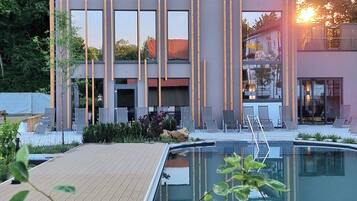 Un edificio moderno con piscina, rodeado de vegetación y árboles.