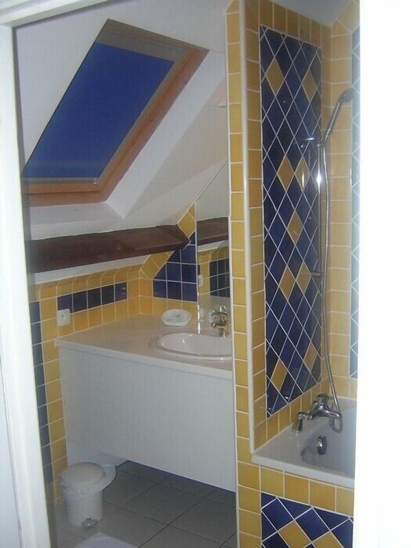 Un baño con tragaluz, lavamanos, espejo y ducha.