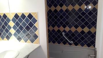 Une salle de bain avec un lavabo blanc, un miroir et une baignoire, ainsi qu’une serviette blanche.