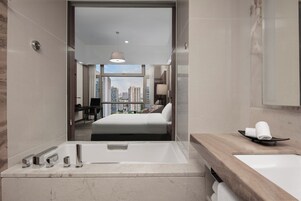 A modern hotel bathroom with a large mirror, a bathtub, and a sink.