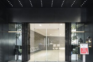 Un'accoglienza moderna con porte in vetro, una reception e un'area d'attesa con panche.