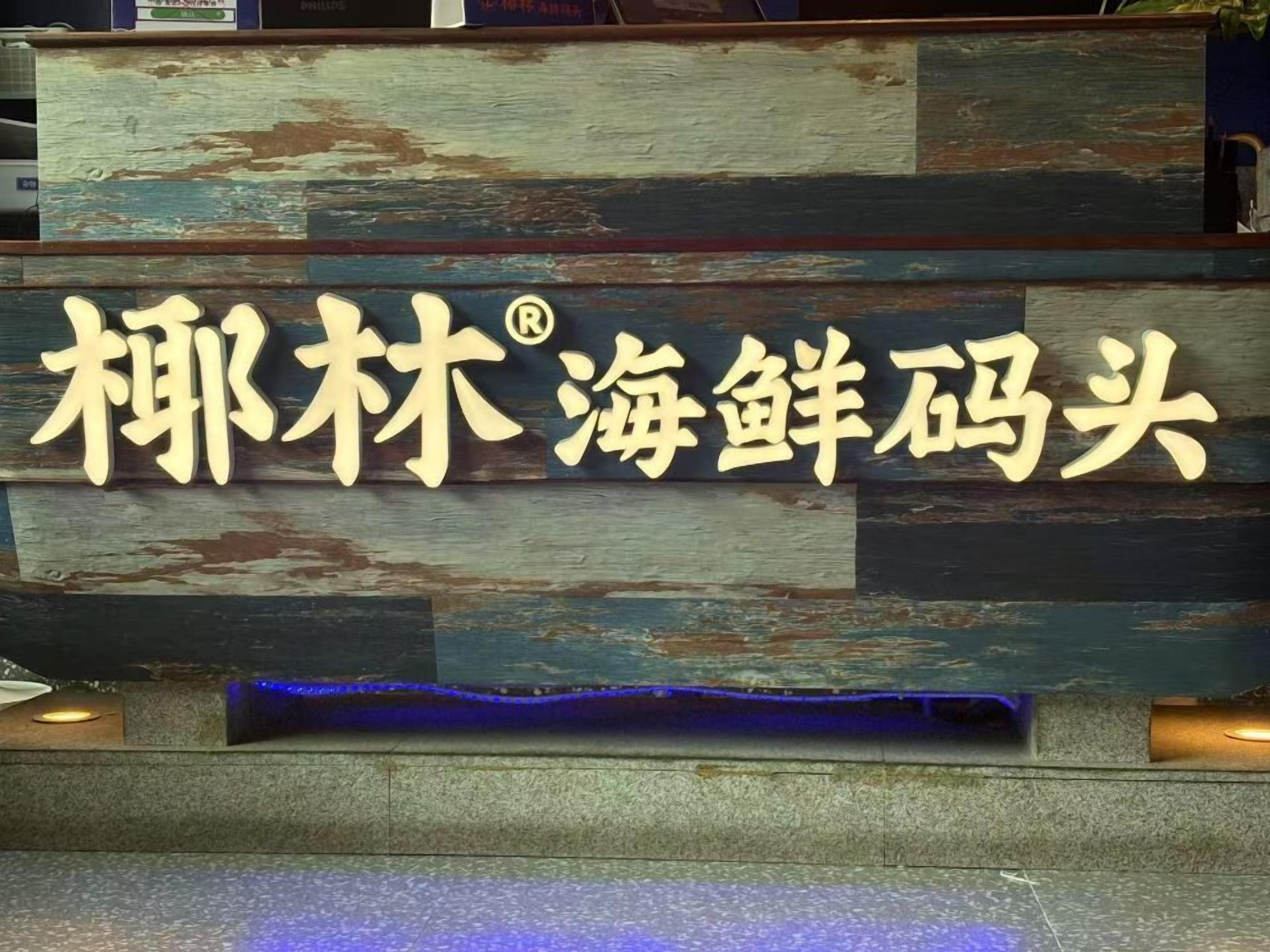 Un letrero con caracteres chinos y un logotipo, probablemente indicando un hotel o restaurante.