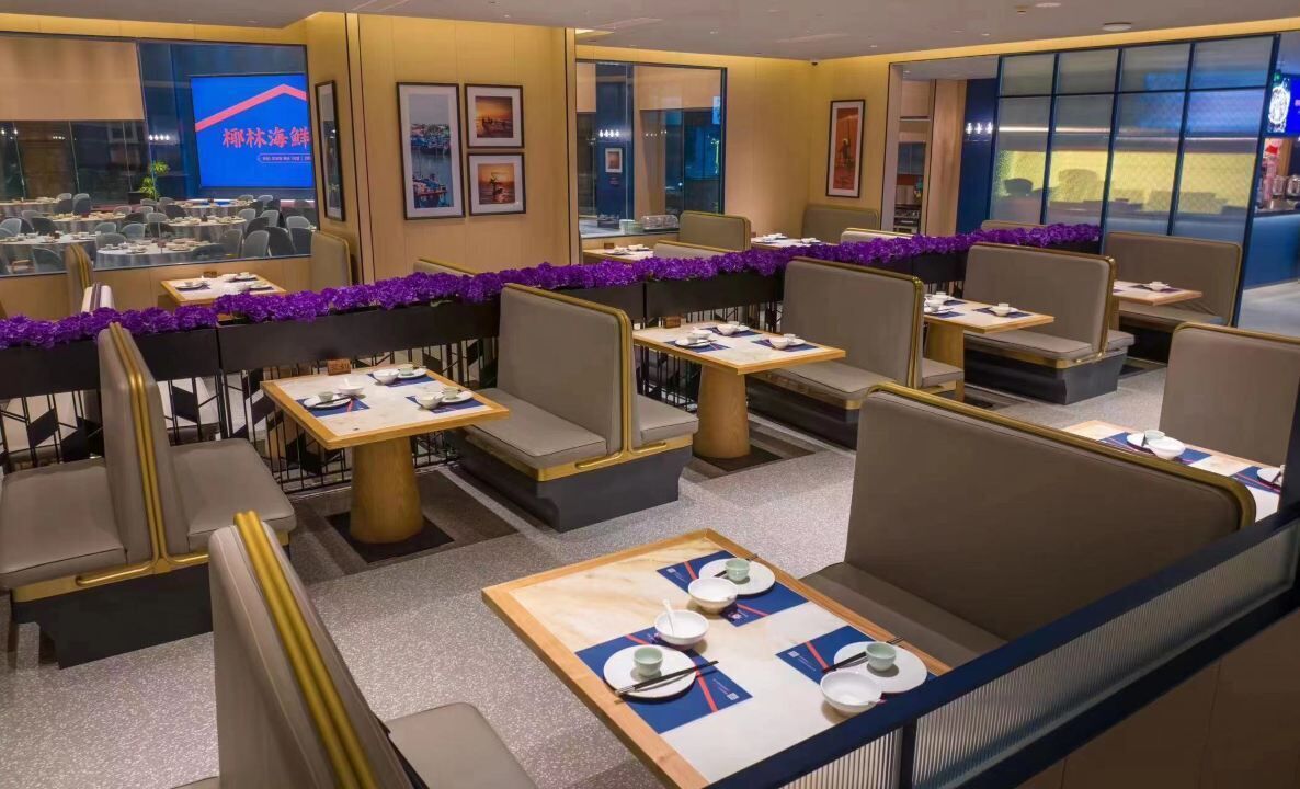 A restaurant with booths and tables, some with purple garlands.