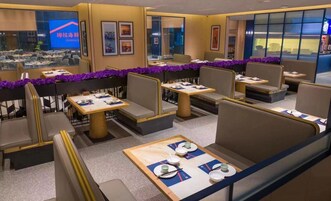 Un restaurante con cabinas y mesas, algunas decoradas con guirnaldas moradas.