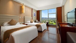 A hotel room with two beds, a desk, a TV, and a large window with a city view. - Empark Grand Hotel (Xishuangbanna Dai)