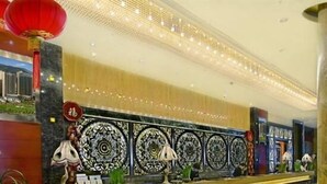 A lobby with a marble reception desk, decorative wall panels, and a red lantern. - Empark Grand Hotel (Xishuangbanna Dai)