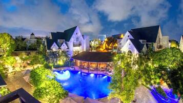 Ein Resort mit Schwimmbad, Bar und einem Gebäude mit spitzer Dachform.