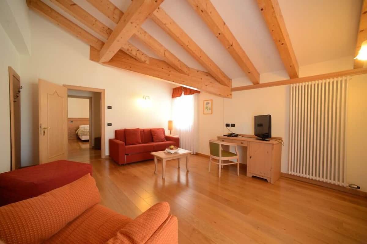 A cozy living room with a wooden ceiling, a red sofa, a small table, and a TV stand.