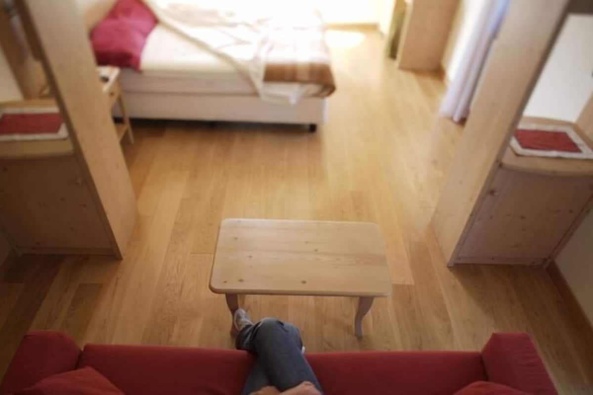 A room with a bed, a small wooden table, and a red sofa.