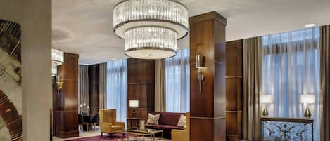 A spacious lobby with a large chandelier, plush seating, and a wooden reception desk.