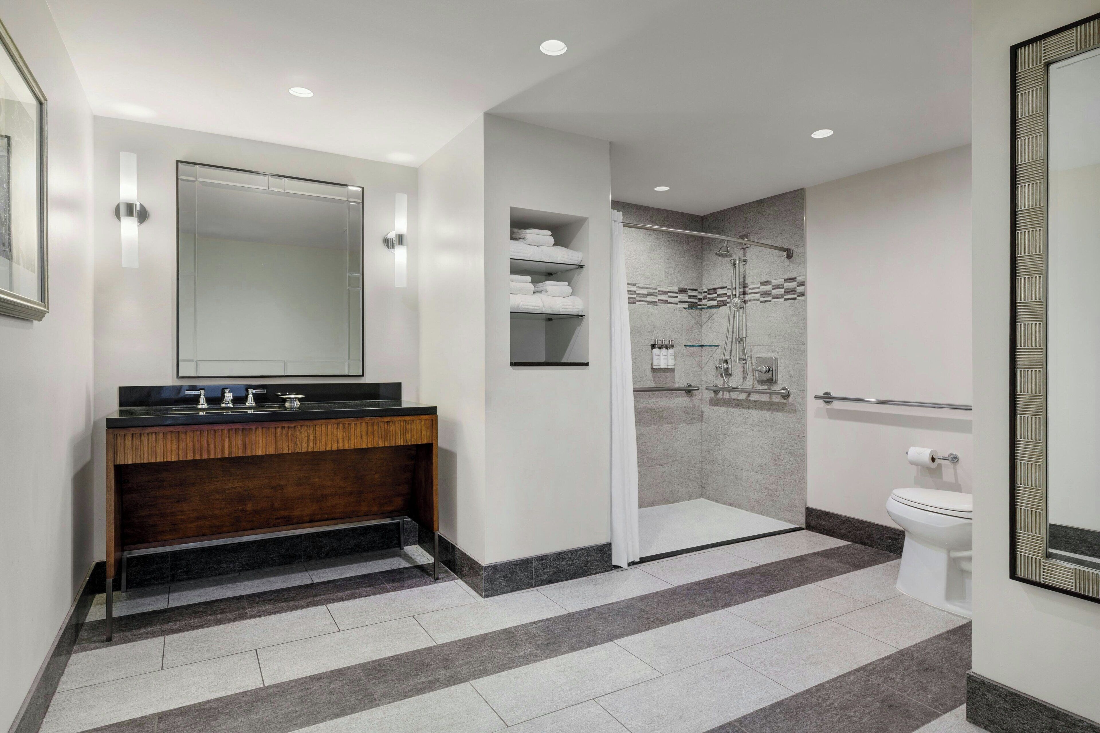 Un baño moderno con tocador, ducha e inodoro.