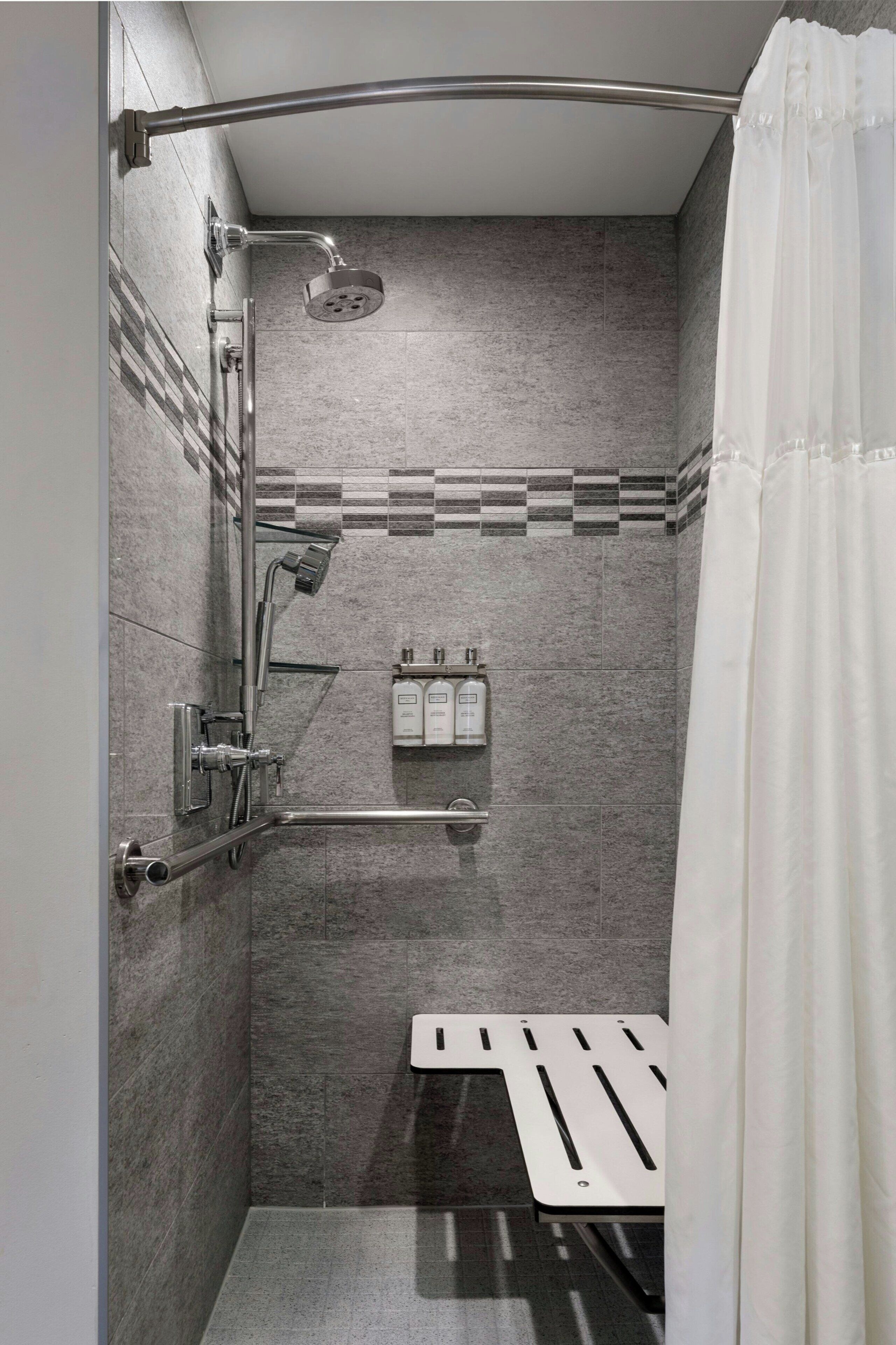 A modern shower with a handheld showerhead, a rain showerhead, and a handheld shower attachment.