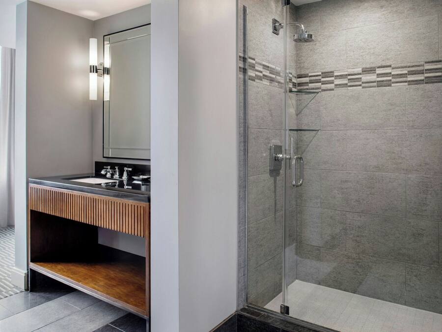 Un bagno moderno con cabina doccia in vetro, mobile lavabo in legno e uno specchio grande.